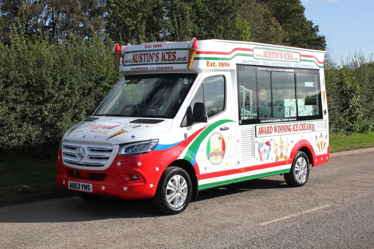 The serving side of the Austins Ices electric ice cream van, showing the hatch window, a sign saying we accept cash and card payments, and Award Winning Ice Cream lettering